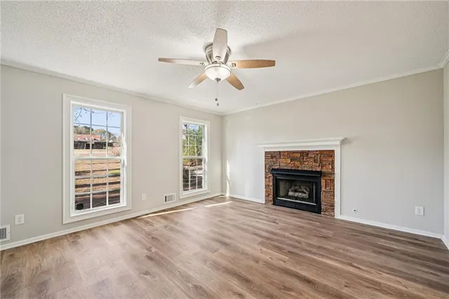 an empty room with windows fireplace and a ceiling fan