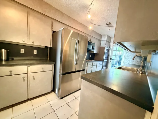 a kitchen with stainless steel appliances granite countertop a refrigerator a stove and a sink with granite countertops