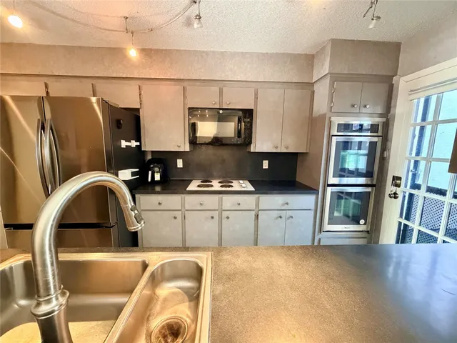 a kitchen with stainless steel appliances granite countertop a refrigerator a stove and a sink with wooden floor