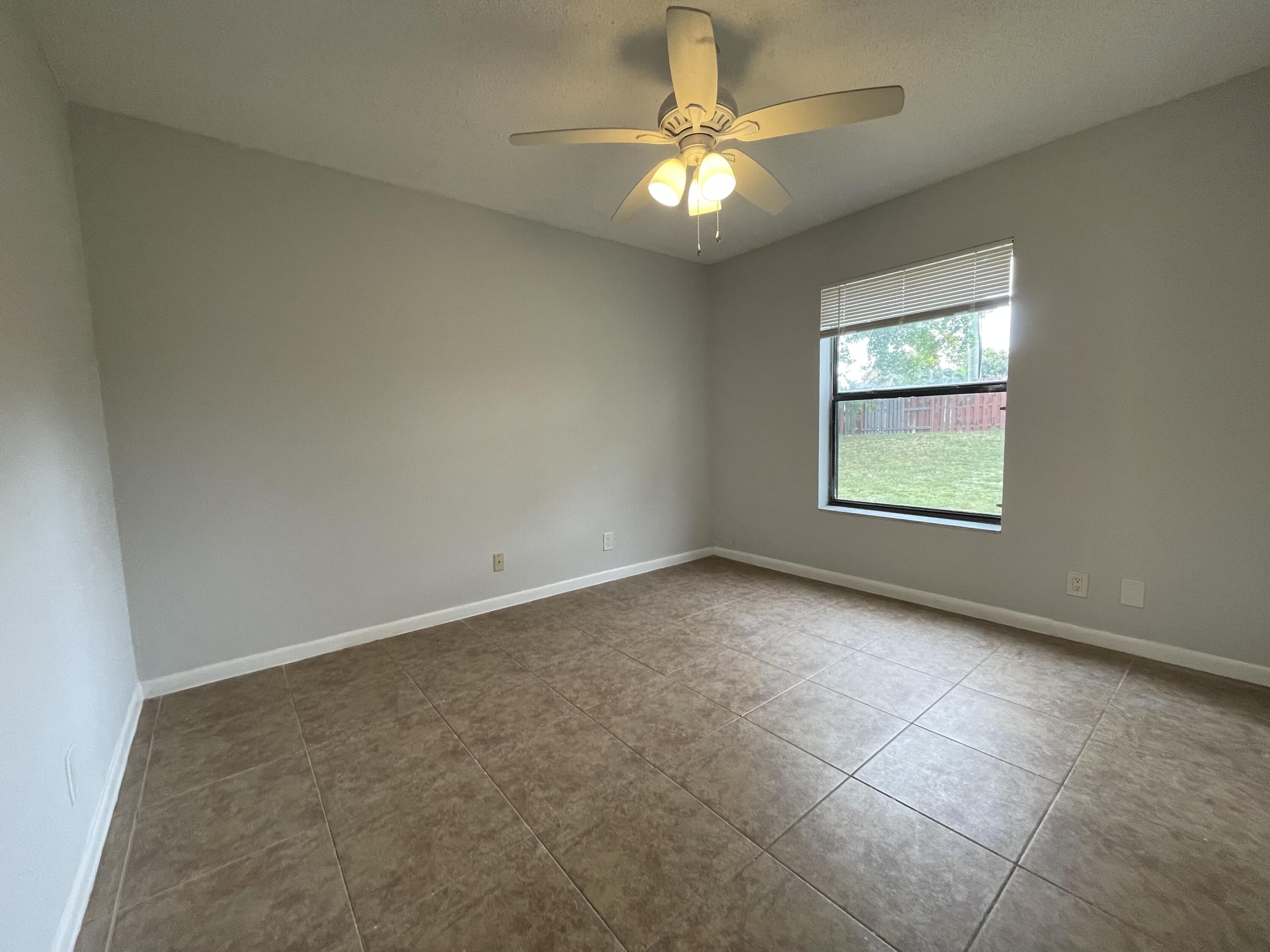 28 Crossings Circle, Unit B Boynton Beach, FL 33435 - Photo 12 of 19 an empty room with a chandelier fan and windows