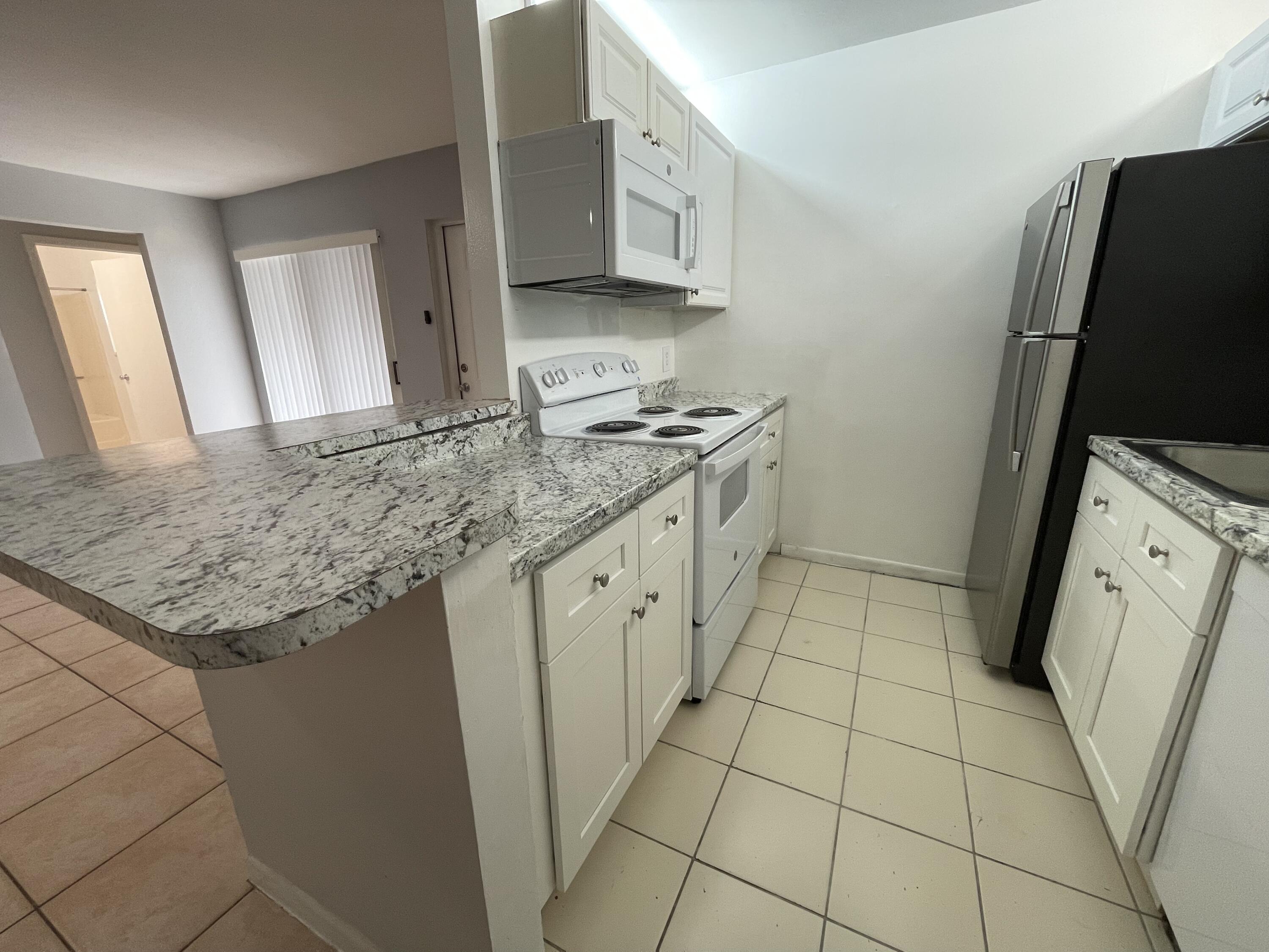 28 Crossings Circle, Unit B Boynton Beach, FL 33435 - Photo 4 of 19 a kitchen with stainless steel appliances granite countertop a sink stove and cabinets