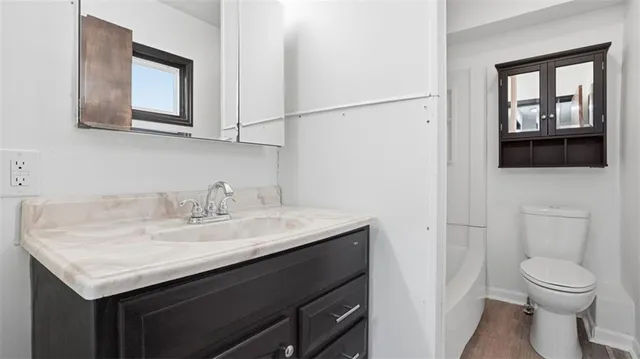 a bathroom with a granite countertop sink toilet and mirror