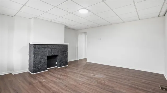 a view of an empty room with wooden floor and a fireplace