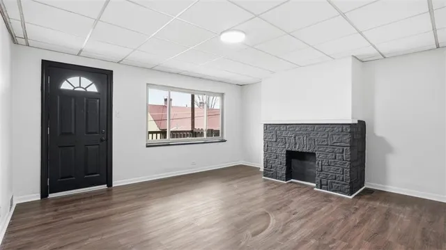 an empty room with wooden floor fireplace and windows