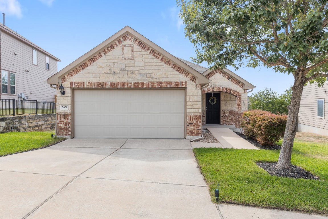 a view of a house with a yard plants and large tree