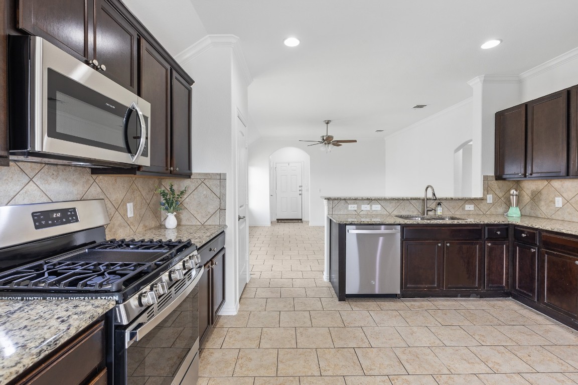 5621 Little Theater Bend Austin, TX 78747 - Photo 14 of 38 a kitchen with stainless steel appliances granite countertop a stove a sink and a microwave