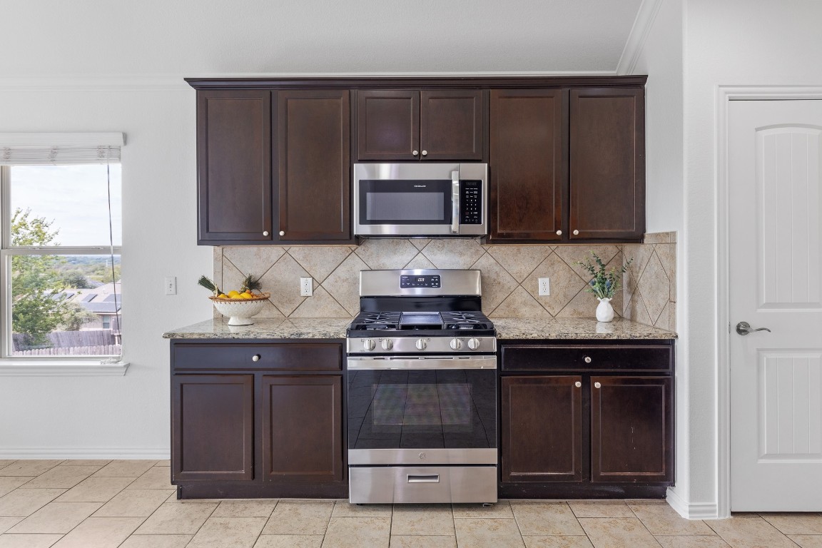 5621 Little Theater Bend Austin, TX 78747 - Photo 9 of 38 a kitchen with granite countertop a stove and a microwave