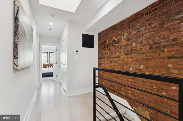 a view of a hallway with wooden floor and a bathroom