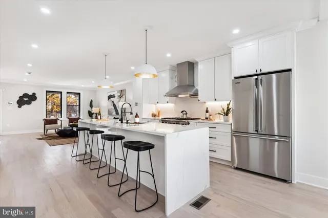 a kitchen with stainless steel appliances granite countertop a refrigerator a sink dishwasher a stove and white cabinets with wooden floor