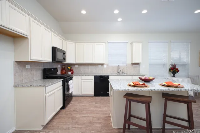 a kitchen with granite countertop a sink stove and cabinets