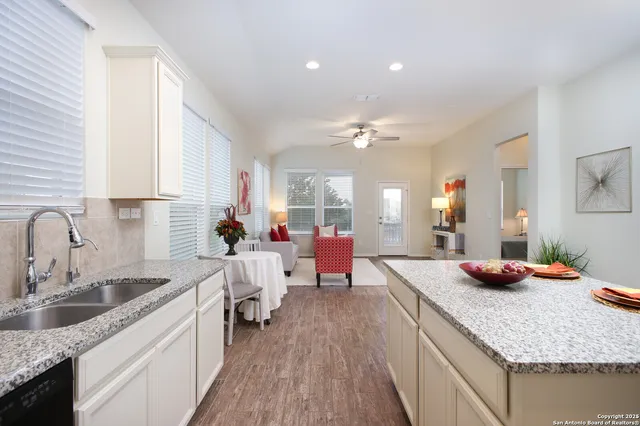 a kitchen with stainless steel appliances granite countertop a sink dishwasher stove and white cabinets with wooden floor
