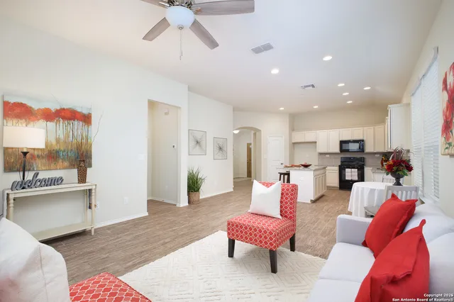 a living room with furniture kitchen view and a wooden floor