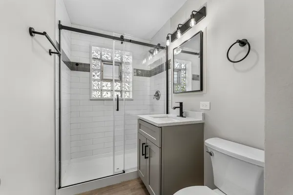 a bathroom with a granite countertop sink mirror vanity and toilet