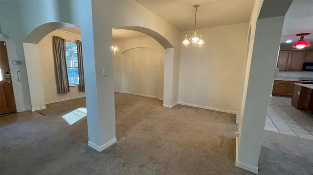 an empty room with fireplace chandelier and windows