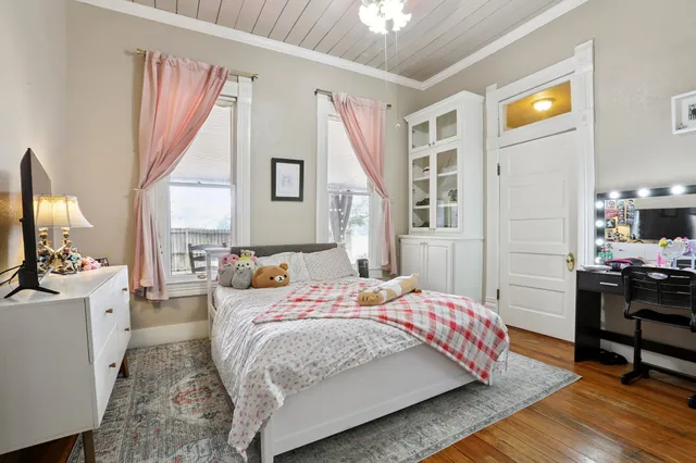 a bedroom with a bed wooden floor and flat screen tv