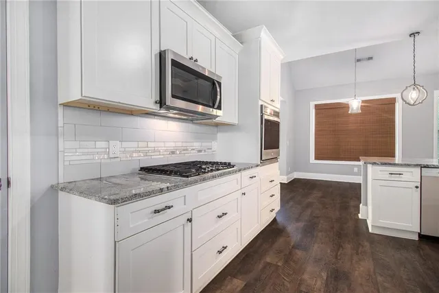 a kitchen with stainless steel appliances granite countertop a stove a sink and a microwave