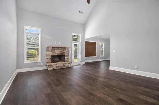 an empty room with wooden floor fireplace and windows