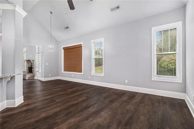a view of an empty room with wooden floor and a window