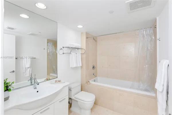 a bathroom with a bathtub shower sink mirror and toilet