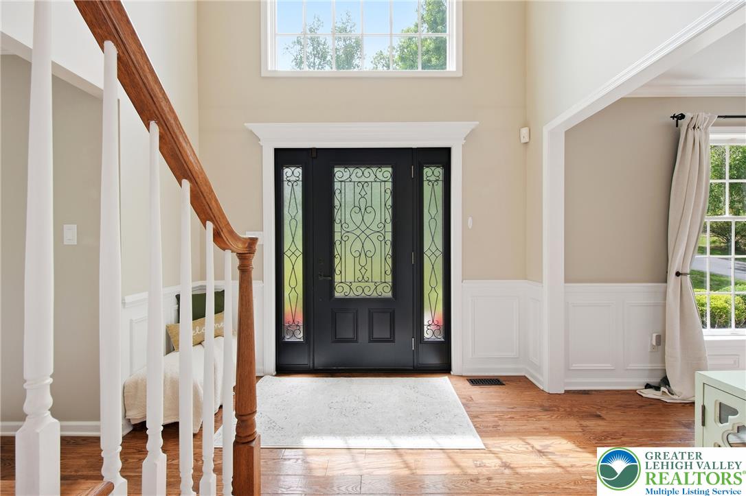 115 West Butternut Road Hellertown, PA 18055 - Photo 11 of 97 A grand entrance welcomes with intricate glass door details and rich hardwood flooring, complemented by wainscoting.