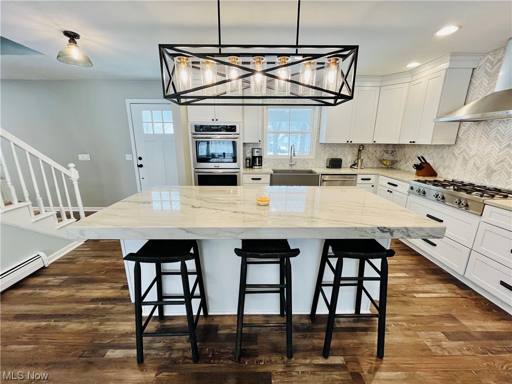 13655 Spring Street Burton, OH 44021 - Photo 26 of 48 Kitchen featuring pendant lighting, dark hardwood / wood-style flooring, appliances with stainless steel finishes, a kitchen island, and light stone countertops