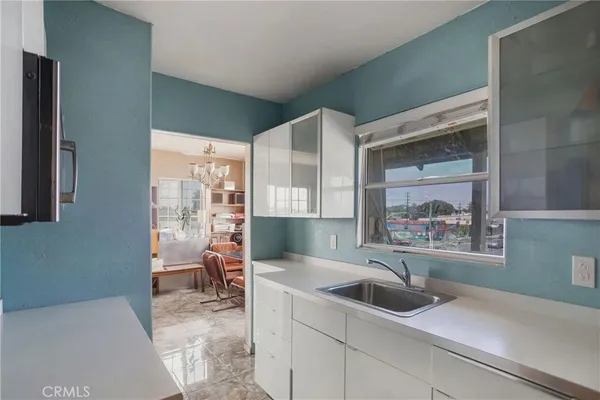 a kitchen with stainless steel appliances granite countertop a sink a refrigerator and a granite counter tops with white cabinets