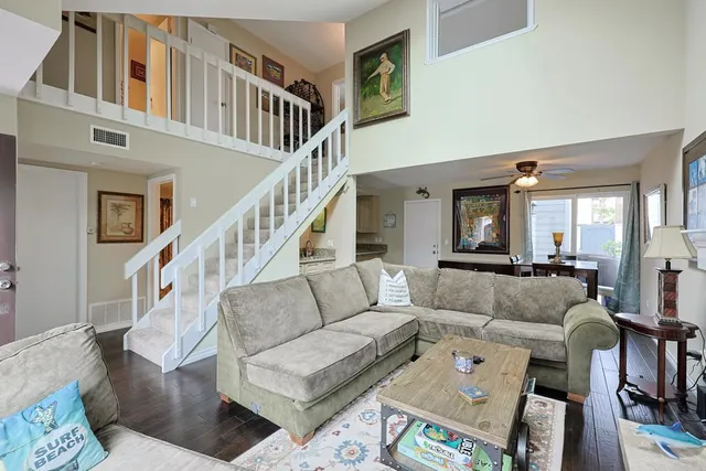 a living room with furniture and a dining table with wooden floor