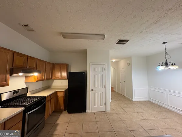 a kitchen with granite countertop a refrigerator and a stove top oven