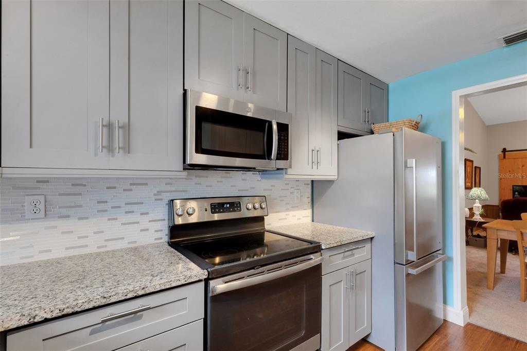 1065 Tartan Drive, Unit C Palm Harbor, FL 34684 - Photo 3 of 91 a kitchen with stainless steel appliances granite countertop a stove microwave and refrigerator