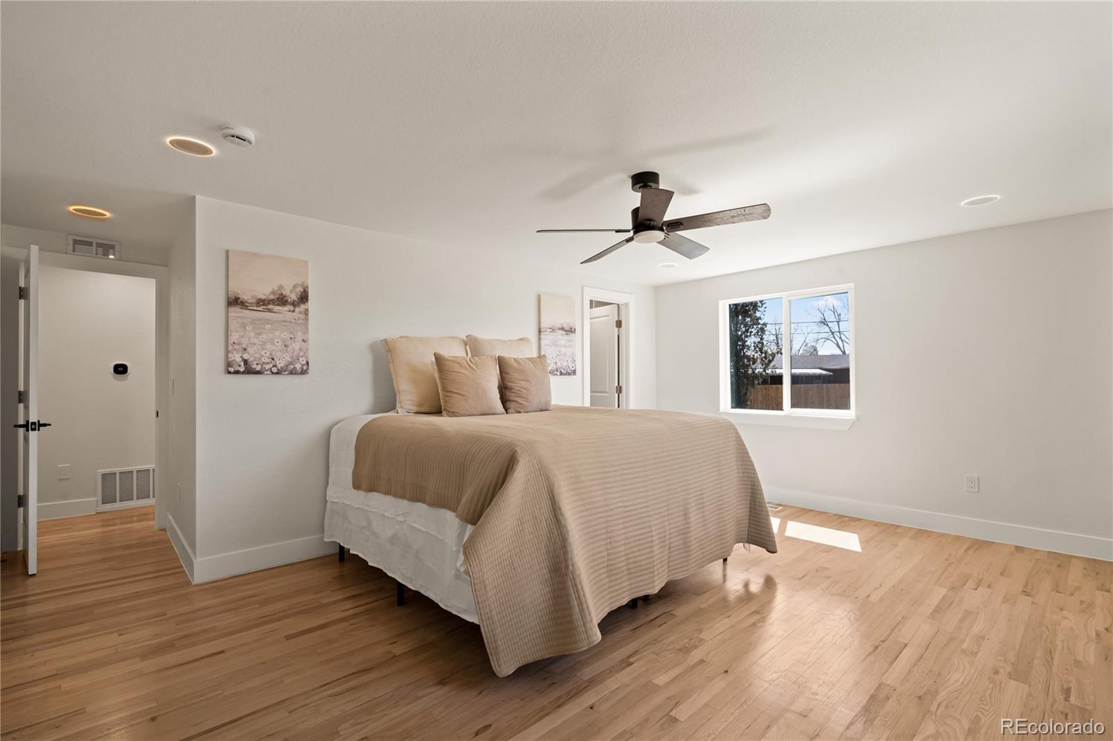 6766 Zenobia Loop Westminster, CO 80030 - Photo 31 of 50 a bedroom with a large bed chandelier and a window