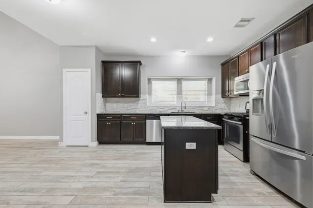 a kitchen with granite countertop a refrigerator and a sink