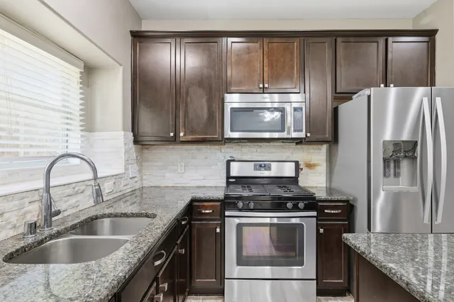 a kitchen with granite countertop a sink stove and refrigerator