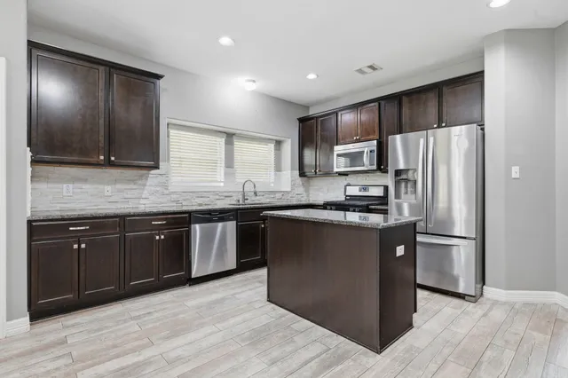 a kitchen with stainless steel appliances granite countertop a refrigerator and a stove top oven
