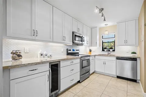 a kitchen with granite countertop white cabinets white stainless steel appliances with a sink and dishwasher