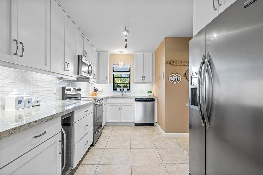 2440 DC Country Club Boulevard, Unit 111C Deerfield Beach, FL 33442 - Photo 3 of 43 a kitchen with a sink refrigerator and cabinets