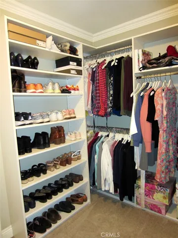 a view of walk in closet with clothes and shoes