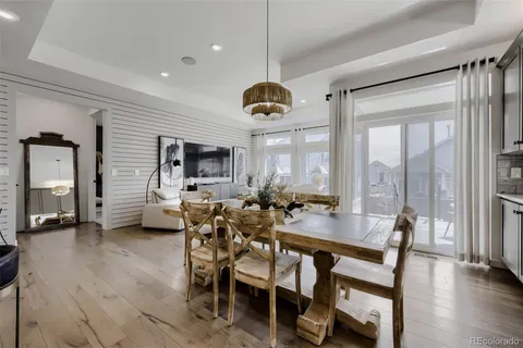 a dining hall with couches a dining table and chairs with wooden floor