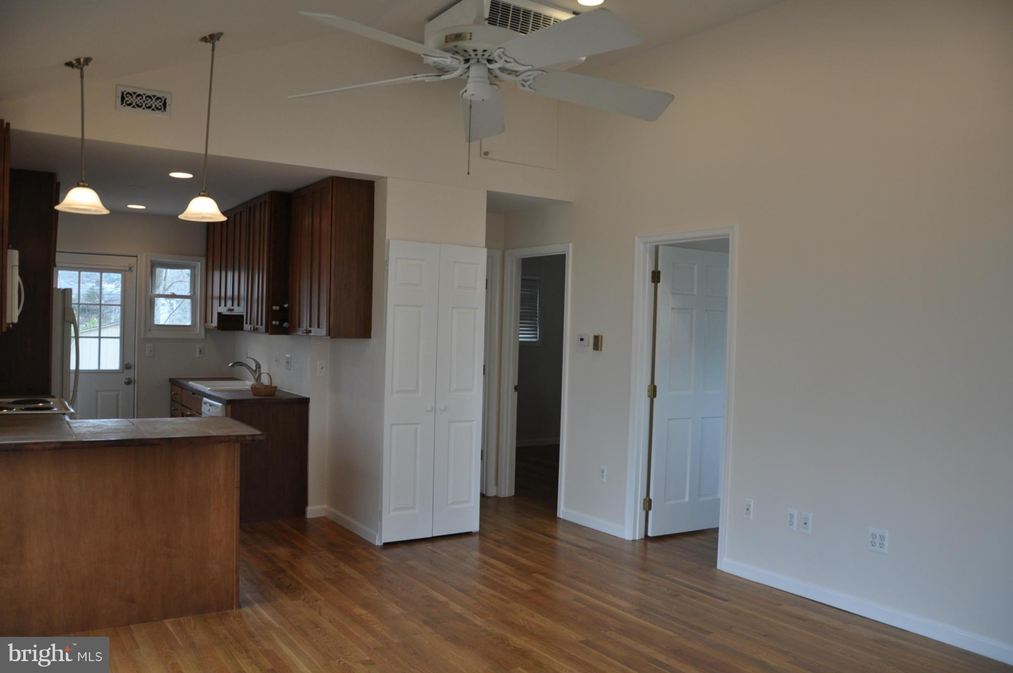 10303 Procter Street Silver Spring, MD 20901 - Photo 9 of 24 an empty room with wooden floor and a kitchen view