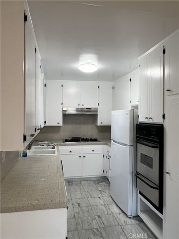 a kitchen with stainless steel appliances a refrigerator sink and white cabinets
