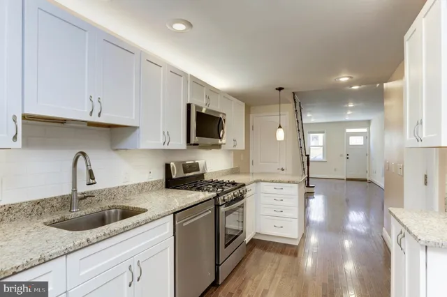 a kitchen with granite countertop a sink stainless steel appliances and white cabinets