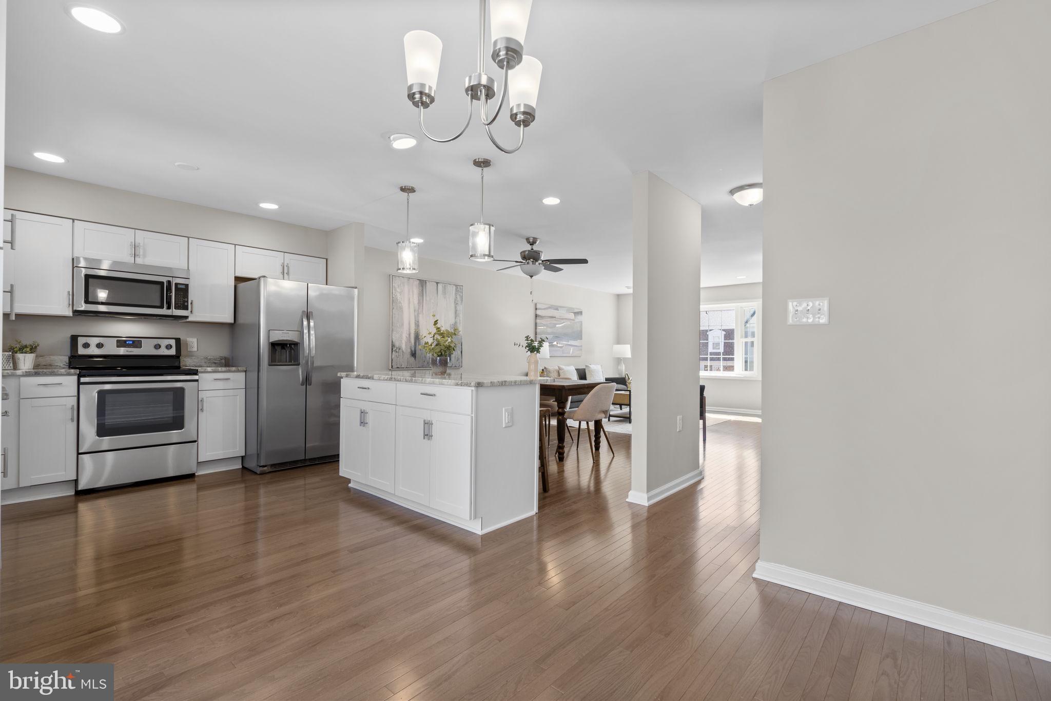 3050 Seminole Road Woodbridge, VA 22192 - Photo 10 of 35 a kitchen with stainless steel appliances kitchen island granite countertop a stove a refrigerator a sink a microwave oven a dining table and chairs with wooden floor