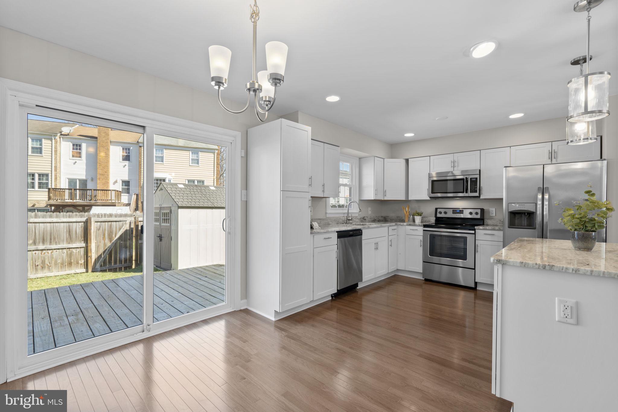 3050 Seminole Road Woodbridge, VA 22192 - Photo 11 of 35 a kitchen with stainless steel appliances granite countertop a refrigerator oven a sink dishwasher a dining table and chairs with wooden floor