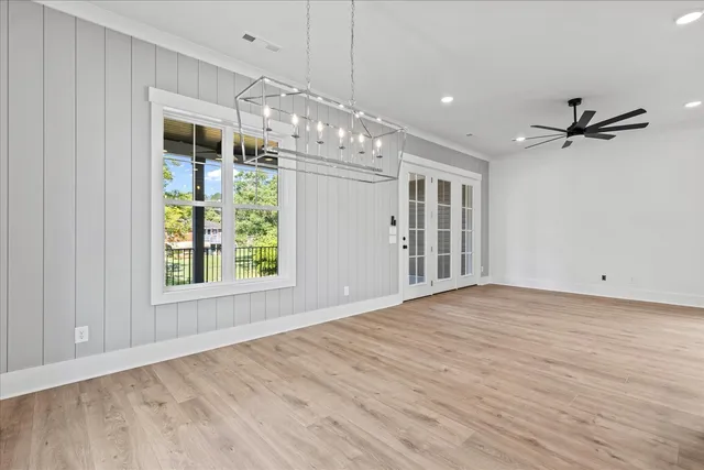 an empty room with wooden floor a ceiling fan and windows