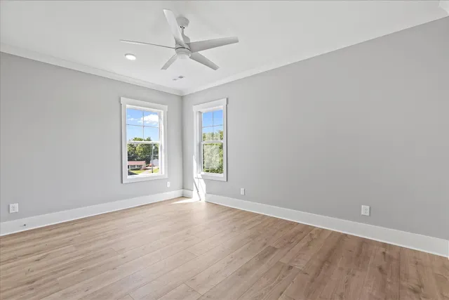 an empty room with wooden floor fan and windows