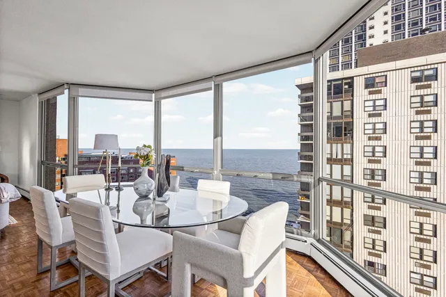 a dining room with furniture water view and a floor to ceiling window
