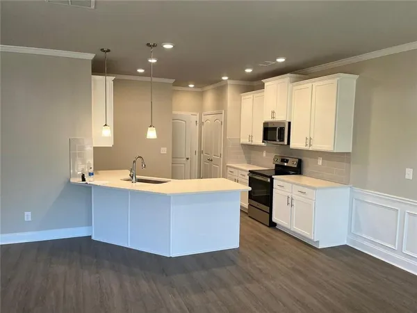 a large kitchen with stainless steel appliances a large counter top a stove a sink and a refrigerator