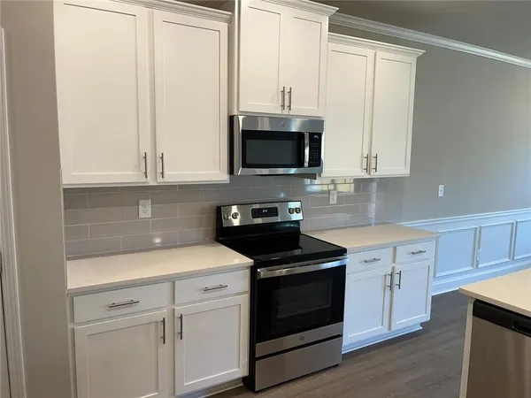 a kitchen with white cabinets and black appliances