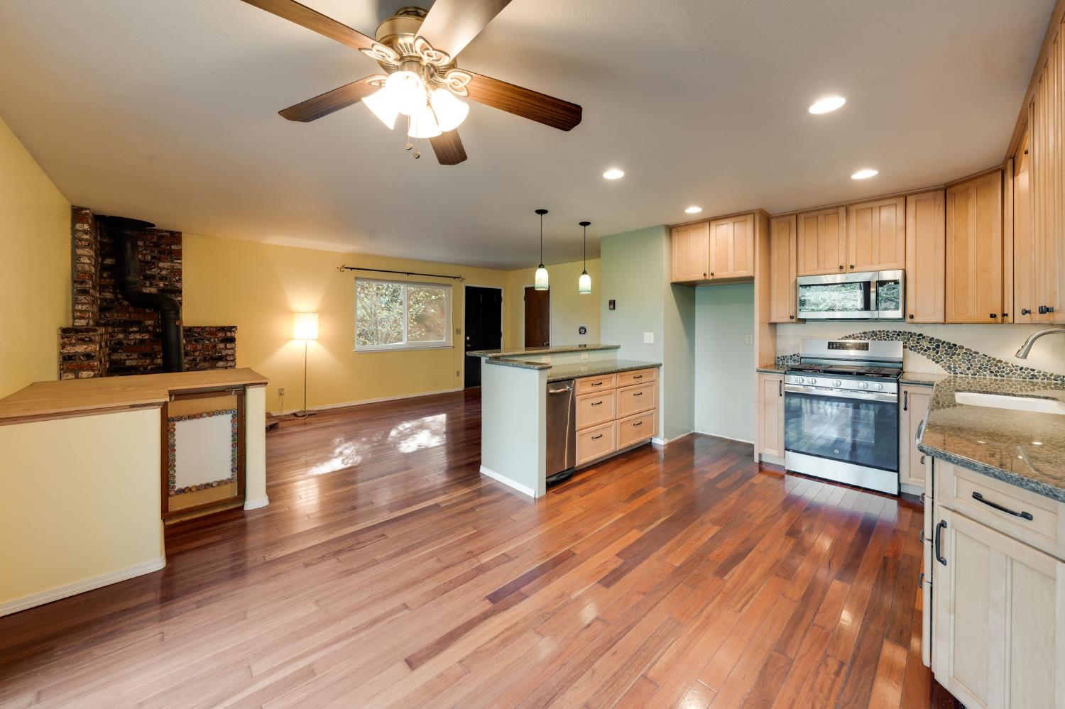 6139 Shad Way Pollock Pines, CA 95726 - Photo 9 of 49 a kitchen with stainless steel appliances kitchen island granite countertop a stove top oven a sink cabinets and wooden floor