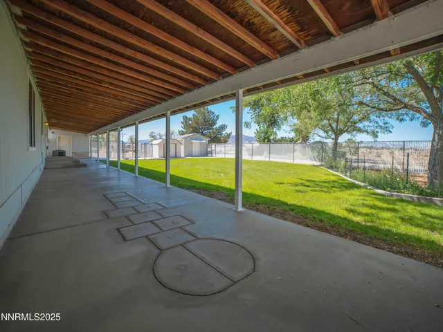a backyard of a house with lots of plants and large tree