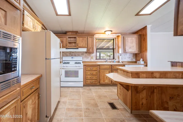 a large kitchen with stainless steel appliances granite countertop a stove a sink and a refrigerator
